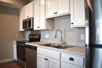 A kitchen with white cabinets and a stainless steel refrigerator.